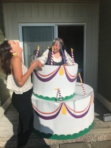 A female psychic dressed like a gypsy coming out of a birthday cake.